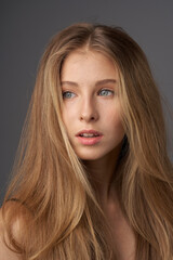 Natural portrait of young beautiful teen age girl with long straight hair. Female model studio shot against grey background. Pretty girl