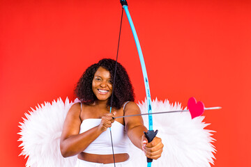 african latin cupid woman in wtite top bra holding bow and arrow in red studio The 14th of February...