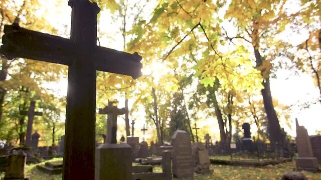 Gravestones with crosses at the Bernardine XIX century cemetery in the sunny Autumn day. Filmed against the sun in slow motion. Vilnius, Lithuania