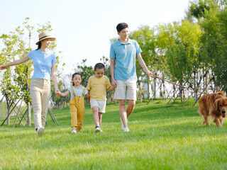Obraz premium Happy family of four walking dogs in the park