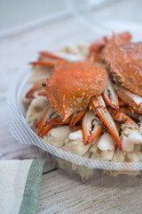 Hot steamed blue swimming crab in circle box on wooden board background.