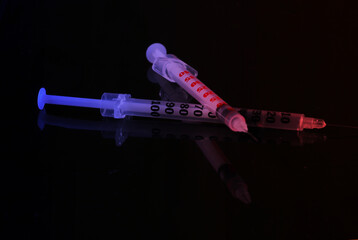 Two syringes isolated on a black background. Vaccination. Neon light