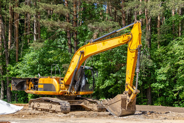 The excavator prepares the site for the construction of the road