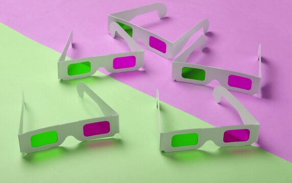 Many stereoscopic anaglyph disposable paper 3d glasses on pink green pastel background.