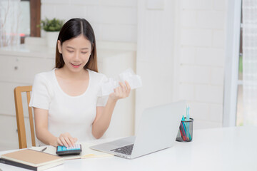 Young asian woman calculating finance household with calculator on desk at home, girl checking bill...