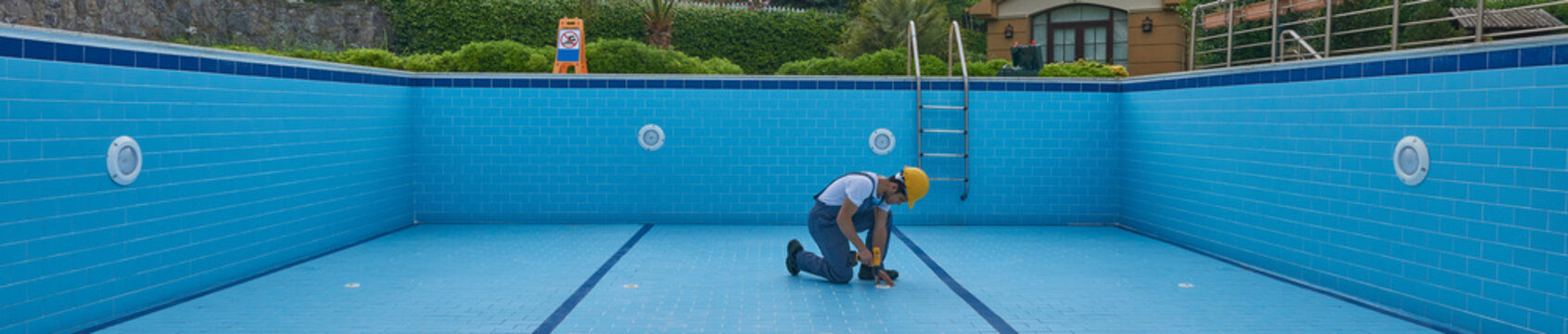 Repairman is repairing pool with equipment. Pool maintenance style.