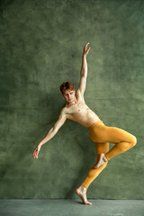 Fototapeta na wymiar Ballet dancer poses at grunge wall, dancing studio