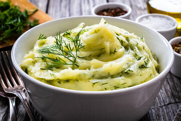 Puree - mashed potatoes with dill in bowl on wooden table