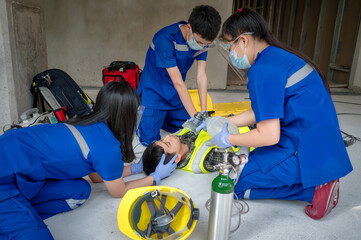 Emergency medical teams are helping unconscious patients by using automated external defibrillators (AED) and providing oxygen. During the rescue of unconscious workers at the construction site