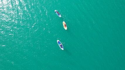 A group of people ride sup surfing in the lake. Aerial view from the drone of the green water and...