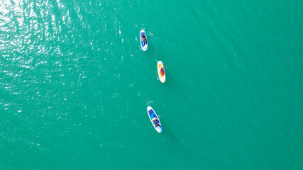 A group of people ride sup surfing in the lake. Aerial view from the drone of the green water and...