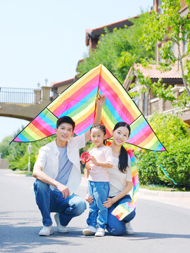 Happy family of three flying kites outdoors