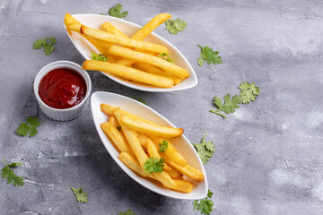 French fries with ketchup in white ceramic cup on gray background