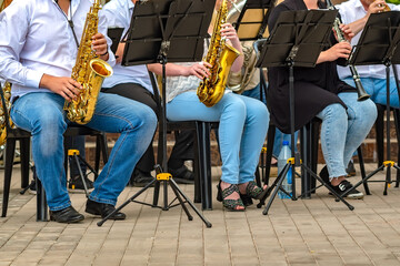 view of a group of people from a musical brass band who are sitting on chairs and playing music,...