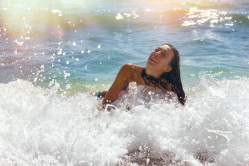 Young girl enjoying the sea waves, carefree vacation after the corona virus pandemic (COVID-19)