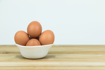 Eggs in white cups lay on wooden floor.