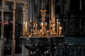 Several long thin candles burn in the darkness of an orthodox church (849)
