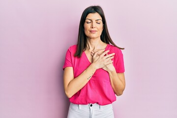 Young hispanic woman wearing casual clothes smiling with hands on chest with closed eyes and grateful gesture on face. health concept.