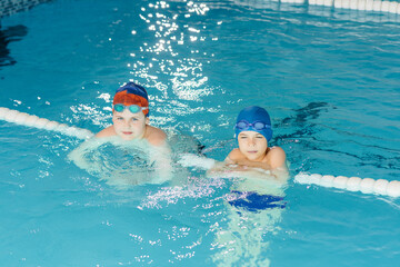 A group of boys and girls train and learn to swim in the pool with an instructor. Development of children's sports.