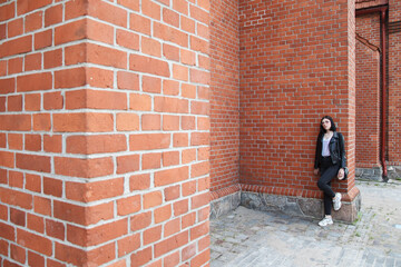 Fototapeta na wymiar young girl stands near the wall of a gothic church