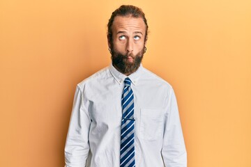 Handsome man with beard and long hair wearing business clothes making fish face with lips, crazy and comical gesture. funny expression.