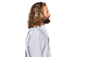 Handsome man with beard and long hair wearing casual clothes looking to side, relax profile pose...