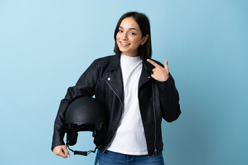 Woman holding a motorcycle helmet isolated on blue background giving a thumbs up gesture