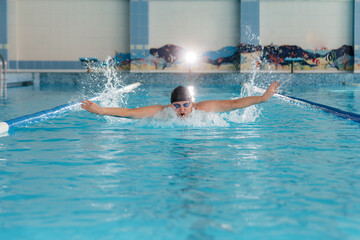 A young athlete trains and prepares for swimming competitions in the pool. Healthy lifestyle.