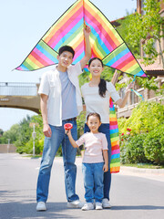Happy family of three flying kites outdoors