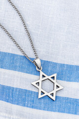 Star of David ("Magen David") with chain on white-blue fabric.