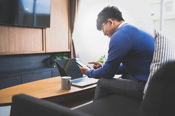 Young attractive man sitting on sofa using smart phone at home.