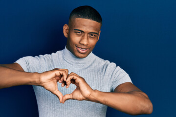 Young black man wearing casual t shirt smiling in love showing heart symbol and shape with hands. romantic concept.