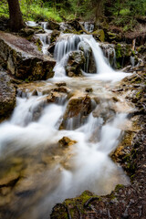 Fototapeta na wymiar Mountain stream cascades over rocks forming a waterfall