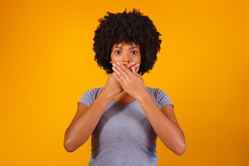 black woman on yellow background with hand in mouth, concept of abuse, feminicide, racism and...