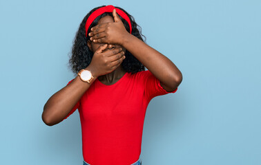 Beautiful african young woman wearing casual clothes covering eyes and mouth with hands, surprised and shocked. hiding emotion