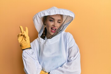 Beautiful blonde caucasian woman wearing protective beekeeper uniform smiling with happy face...