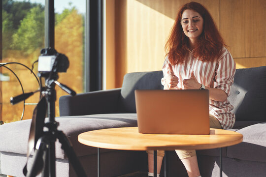 Front view of business woman recording video webinar with digital camera, tripod and laptop