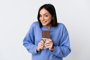 Young caucasian woman isolated on white background taking a chocolate tablet and happy
