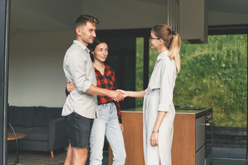 Millennial couple bought a house and shake hands with a realtor 