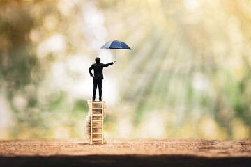 Businessman stand on the gold coin with growing interest and hand hold open the black umbrella for...