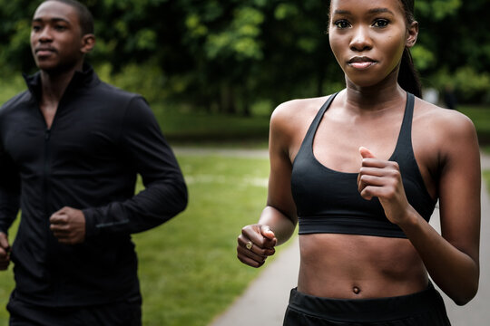 Black brother and sister twins running outdoors in stylish sportswear.