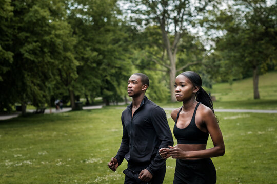 Black brother and sister twins running outdoors in stylish sportswear.