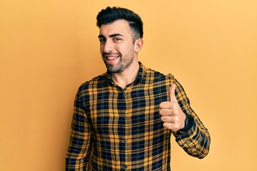 Young hispanic man wearing casual clothes doing happy thumbs up gesture with hand. approving expression looking at the camera showing success.