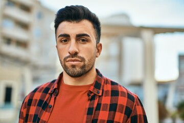 Fototapeta premium Young hispanic man with serious expression standing at the city.