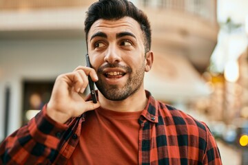 Young hispanic man smiling happy talking on the smartphone at the city.