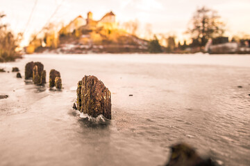 old rotten wooden posts on frozen lake in golden light, Bad Iburg, Germany
