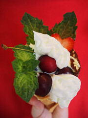 Summer dessert on red background, ice cream with fruits in waffle cones