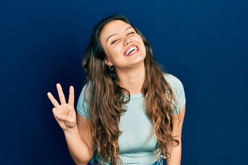 Young hispanic girl wearing casual clothes showing and pointing up with fingers number three while smiling confident and happy.