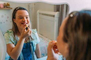 A latin girl with down syndrome putting on her make up with a smile.