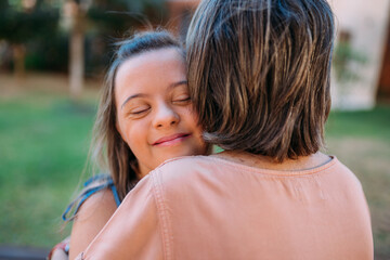 World Down Syndrome Day theme the young girl with Down syndrome with her mother’s in the park. Mother’s Day concept.